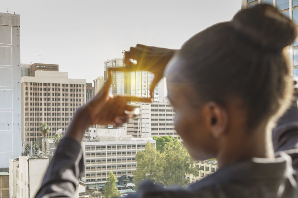 A young business woman framing a building downtown with her fingers
